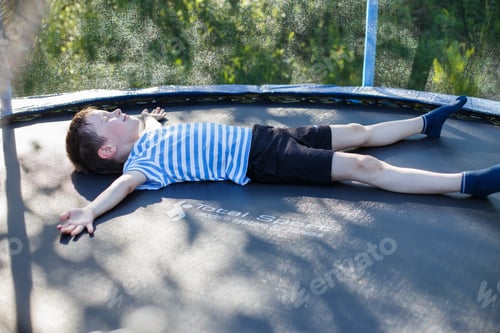Preview: boy on the trampoline. the child lies on a trampoline and rests