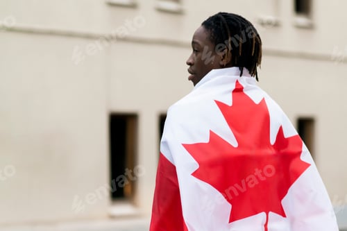 Preview: a black male person holding a flag of canada outdoors, concept of patriotism and independence