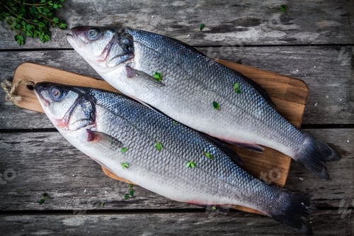 Preview: two raw fresh sea bass on a cutting board with thyme
