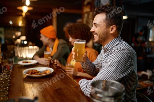 Preview: Happy smiling man sitting at sports bar counter desk looking at camera