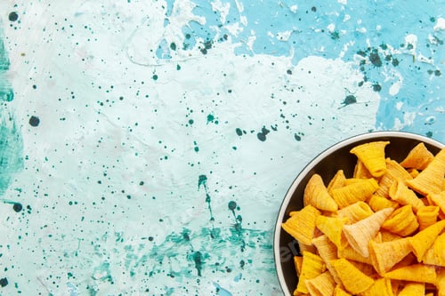 Preview: top close view little spicy chips inside plate on light-blue background chips snack color crisp