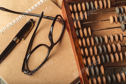 Preview: Desk setup with abacus, notebook, pen, and glasses showcasing a creative workspace