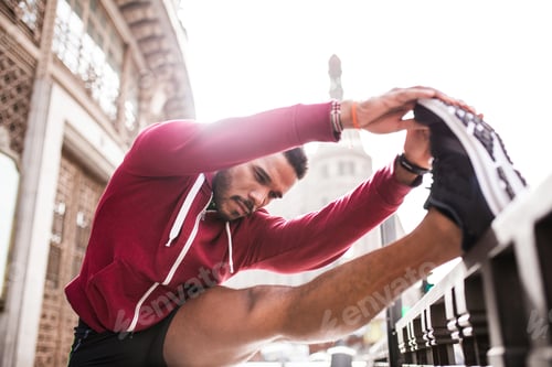 Preview: Young man stretching legs in the street