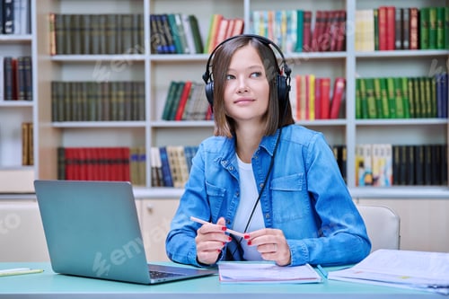 Preview: Young female university student studying inside library