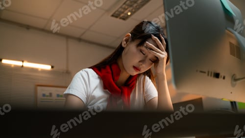 Preview: Young Asian businesswoman suffering from headache and working overload in office at night