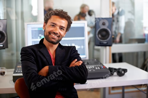 Preview: A handsome music producer sitting with arms folded in his studio