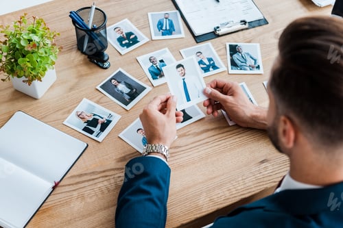 Vista previa: selective focus of recruiter choosing while holding photo near wooden table
