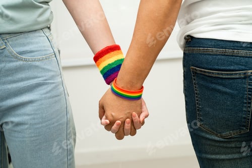 Preview: Asian LGBT couple woman holding hand wearing rainbow wristband.