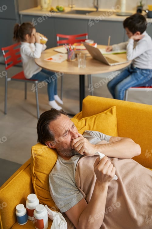 Preview: Diseased man coughing while lying on couch