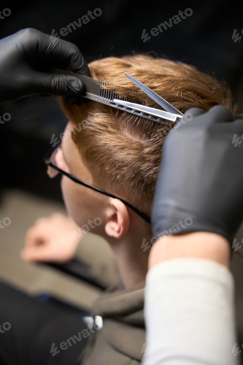 Preview: Cropped view of Caucasian hairstylist serving visitor in hairdressing salon