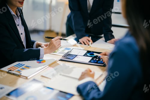 Preview: Business people having a meeting, analyzing financial charts and graphs using digital tablet and doc
