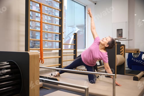 Preview: Middle aged woman stretching after injury during recovery in rehabilitation gym