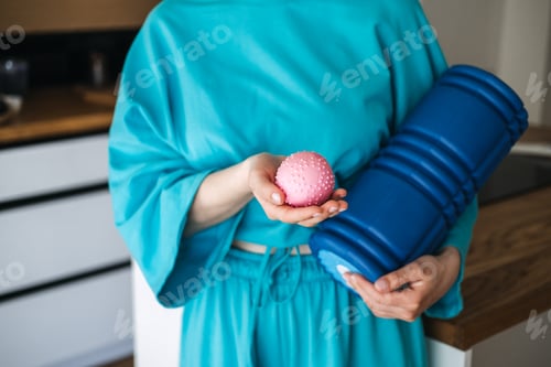 Preview: Woman holding a textured massage ball and foam roller for self-care and muscle recovery. Wellness