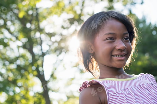 Preview: A young girl with short hair in a striped sundress smiling.