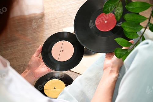Preview: Vinyl records on a wooden table. The girl's hand examines vinyl records. Retro style. So