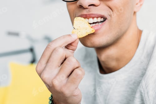 Preview: cropped view of man in white sweatshirt eating chips