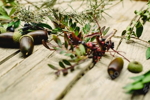 Preview: Aged wooden table background decorated with acorns, red berries and dried leaves.