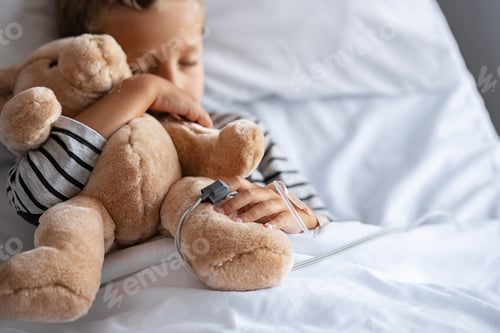 Preview: Little boy sleeping in hospital bed with teddy bear