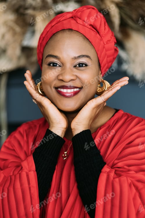 Preview: Traditional African beauty. Beautiful cheerful woman in red dress, headscarf and jewelry posing