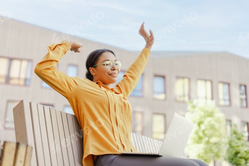 Preview: Confident smiling African American businesswoman stretching hands while using laptop