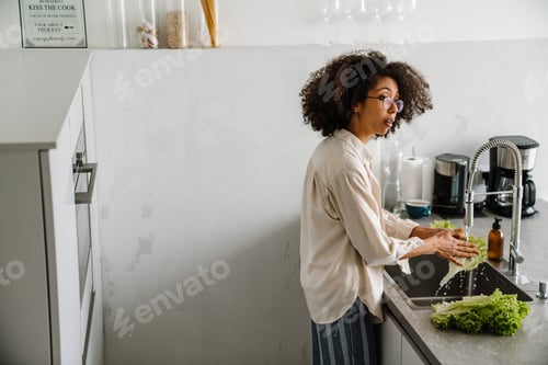 Preview: Woman Washing Green Lettuce at Kitchen Sink