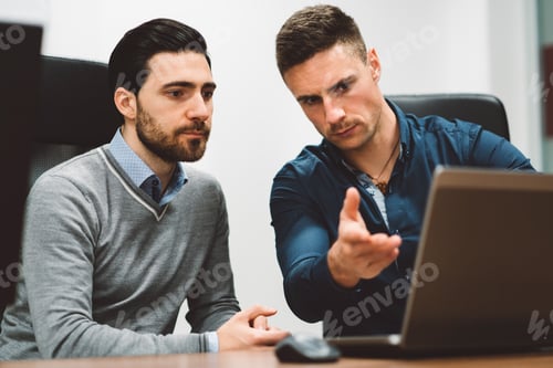 Preview: Couple of colleagues at a start up company working on laptop discussing an issue that needs to be