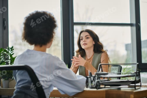 Preview: Colleagues Engaged in Conversation During Layoff Discussions in a Modern Office Setting