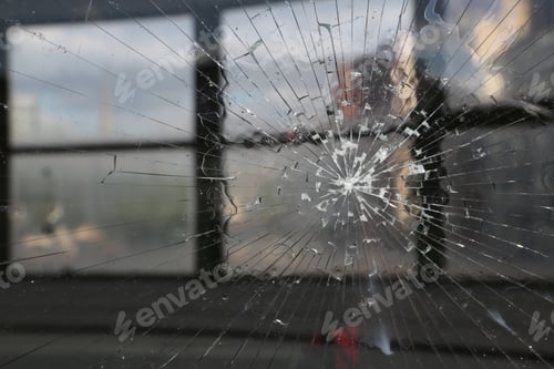 Preview: Closeup shot of a cracked window during sunset with windows in the background