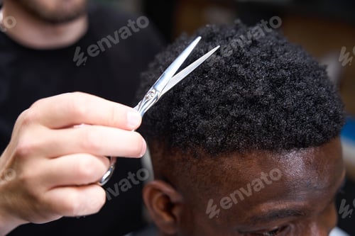 Preview: Hairdresser makes an African American haircut for a client