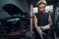 Preview: Auto-mechanic wearing welding gauntlets and protective helmet