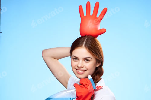Preview: cheerful pretty woman holding an inflated rubber glove above her head cleaning