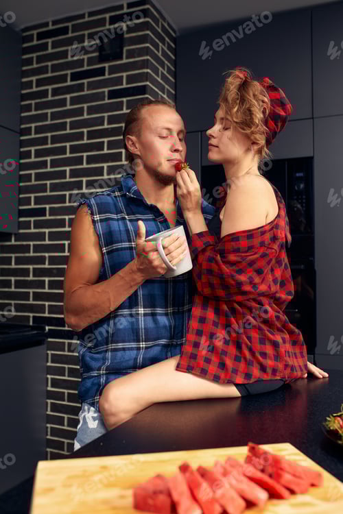 Preview: Happy couple standing in kitchen at home preparing together yummy dinner on first dating, spouses