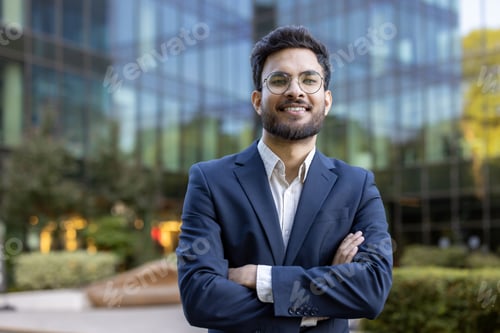 Preview: Confident young business professional standing in front of modern office building with arms crossed