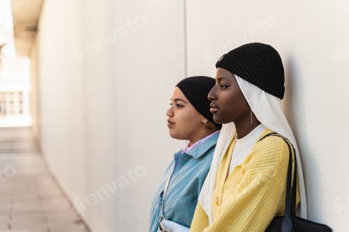 Preview: Portrait of two serious and thoughtful muslim women leaning against a building wall