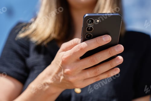 Preview: Close up of woman holding smartphone in hand outdoors