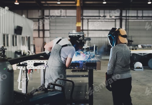Preview: A female welder teaches a child how to weld in a workshop