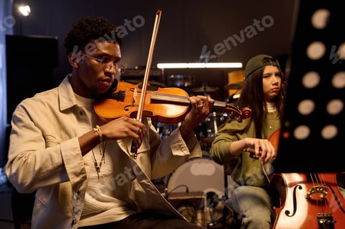 Visualização: Jovem negro e garota tocando instrumentos de corda durante o ensaio