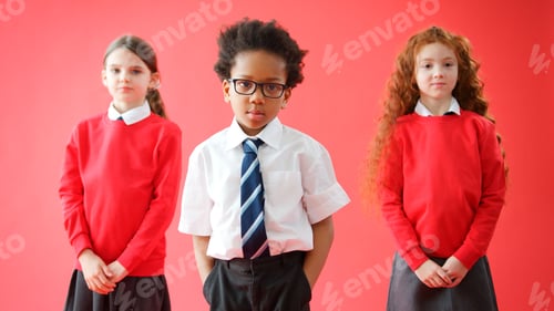Preview: Group Of Elementary School Pupils Wearing Uniform Folding Arms Against Red Studio Background