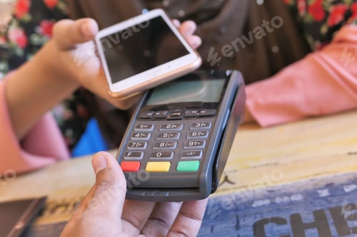 Preview: A customer making a contactless payment with a smartphone in a cafe using a mobile wallet