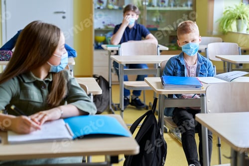 Preview: School children in protective face masks sitting in the classroom