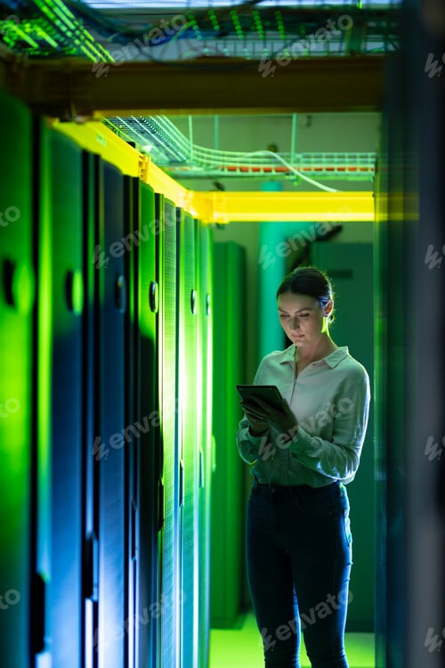 Preview: Caucasian female engineer using digital tablet while inspecting in computer server room