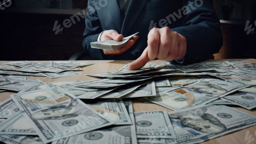 Preview: Man counting heap dollars at office desk close up. Calculating american money.
