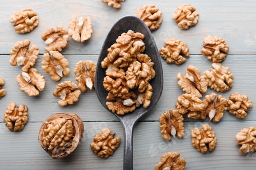 Preview: Old spoon with walnut kernels on wooden table close up