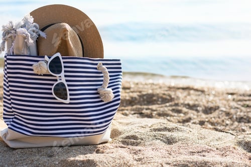 Preview: Beach bag straw hat and glasses plaid on white caribbean sand with turquoise water mockup copy space