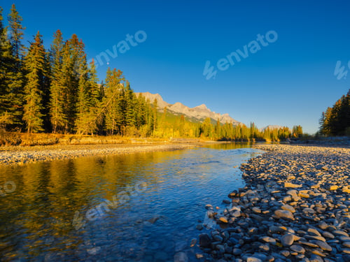 Preview: Landscape during sunrise. Autumn trees on the river bank. Mountains and forest