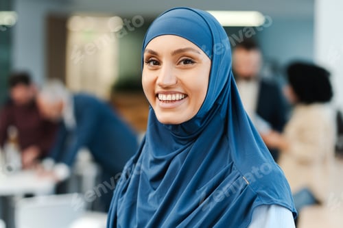 Preview: Smiling attractive confident business woman wearing hijab looking at camera standing in office