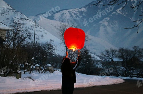 Preview: Woman from behind preparing to release a red lantern skyward in celebration of Chinese New Year.