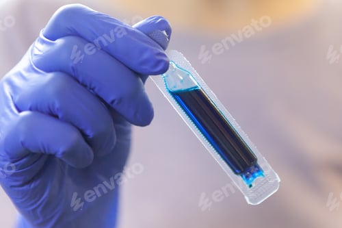 Preview: Blue paint for Easter eggs. The woman is holding a dye capsule. Close-up