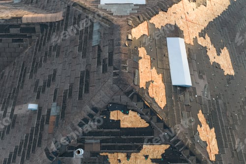 Preview: Wind damaged house roof with missing asphalt shingles after hurricane Ian in Florida.