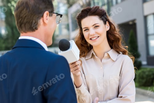 Preview: smiling anchorwoman with microphone interviewing professional businessman